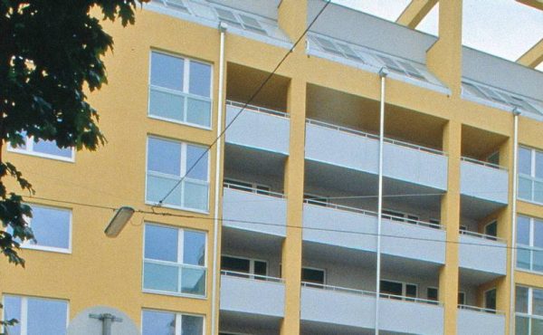 Gelbes modernes Wohngebäude mit Balkonen. Ideal für Wohnungskauf in zentraler Lage.