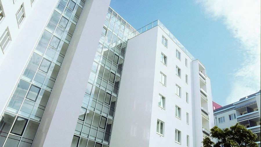 Moderne Wohngebäude mit Glasfassade bei klarem Himmel, Architektur im zeitgenössischen Stil.