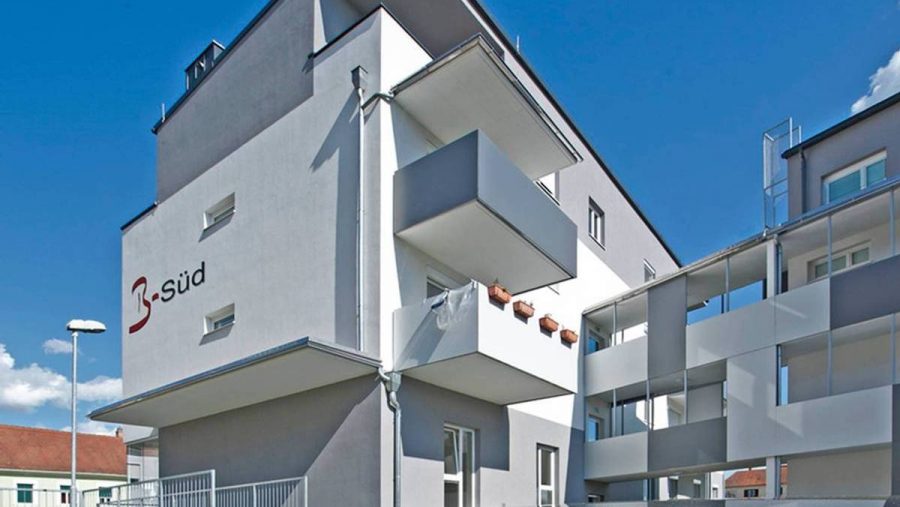 Modernes Mehrfamilienhaus mit Balkon in Wien bei sonnigem Wetter. Ideal für Wohnungskauf im urbanen Umfeld.