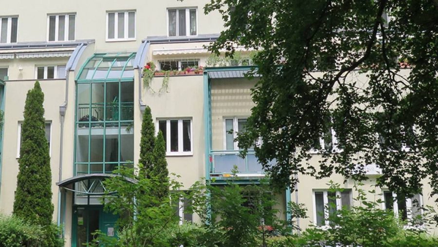 Moderne Wohnanlage mit grüner Fassade und Balkonen in ruhiger Lage, ideal für Wohnungskäufer in Wien.