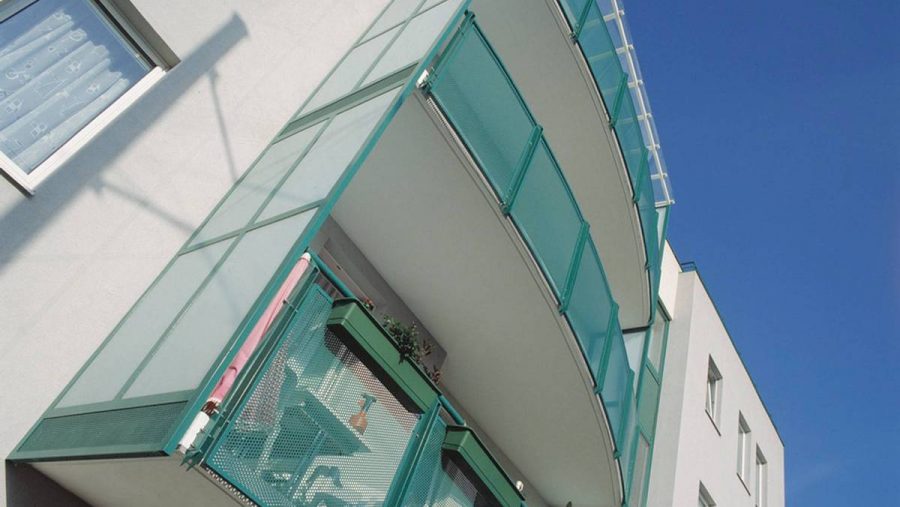 Moderner Balkon einer Wohnung in Wien mit grünem Geländer und Pflanzen auf dem Tisch. Ideal für Wohnung kaufen.