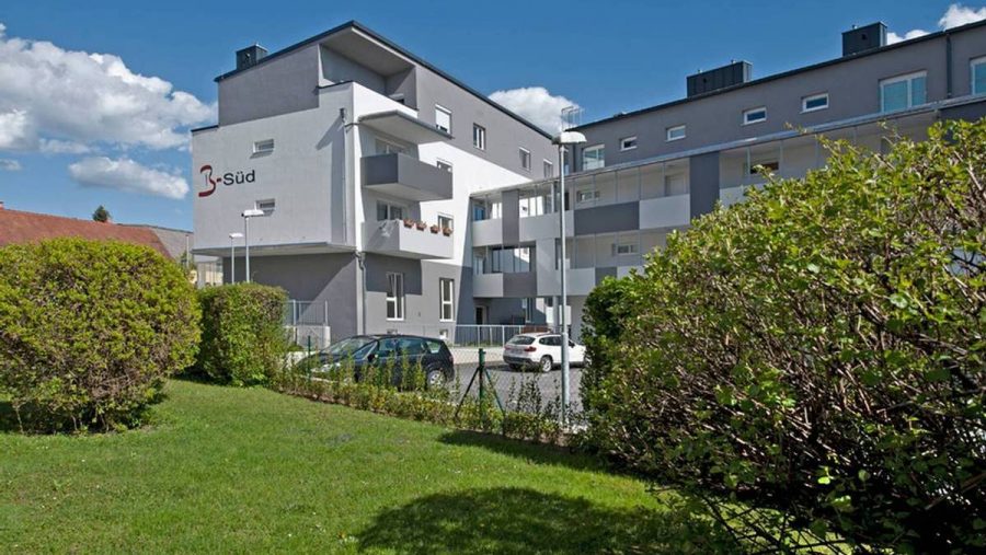 Moderne Wohnanlage in Wien mit gepflegtem Garten und Stellplätzen für Autos. Ideal für Wohnungskäufer.