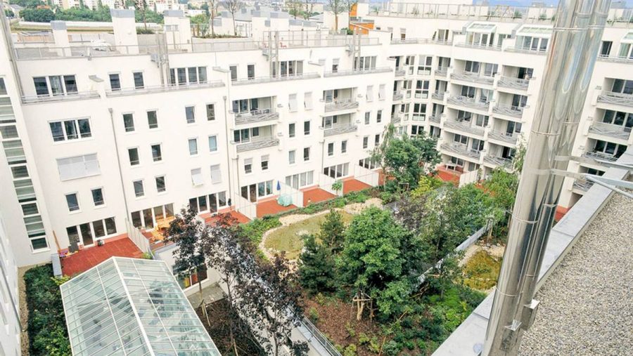 Blick auf die moderne Wohnanlage mit grünem Innenhof in Wien, ideal für Wohnungskäufer.