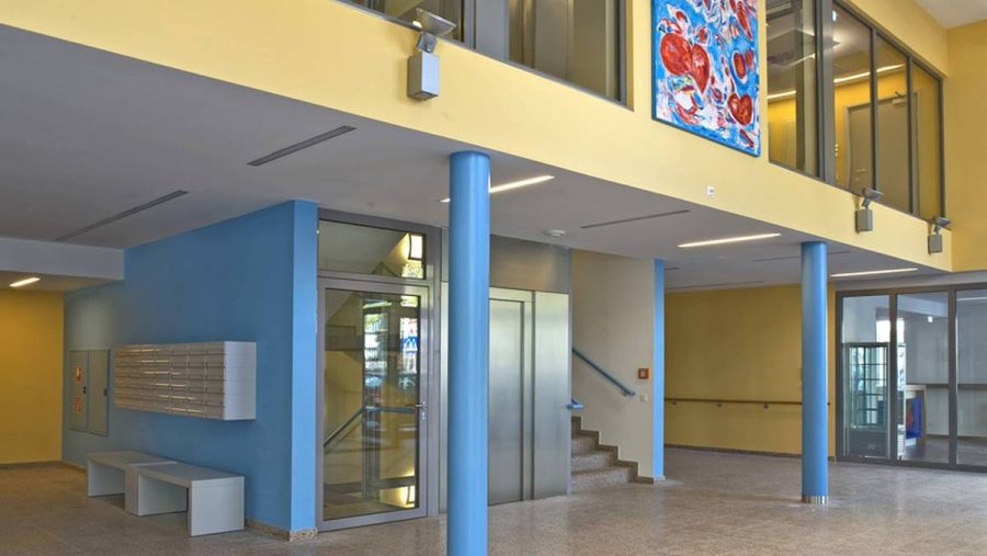 Moderner Eingangsbereich mit Treppe und Kunstwerk in einem Wohnhaus in Wien.