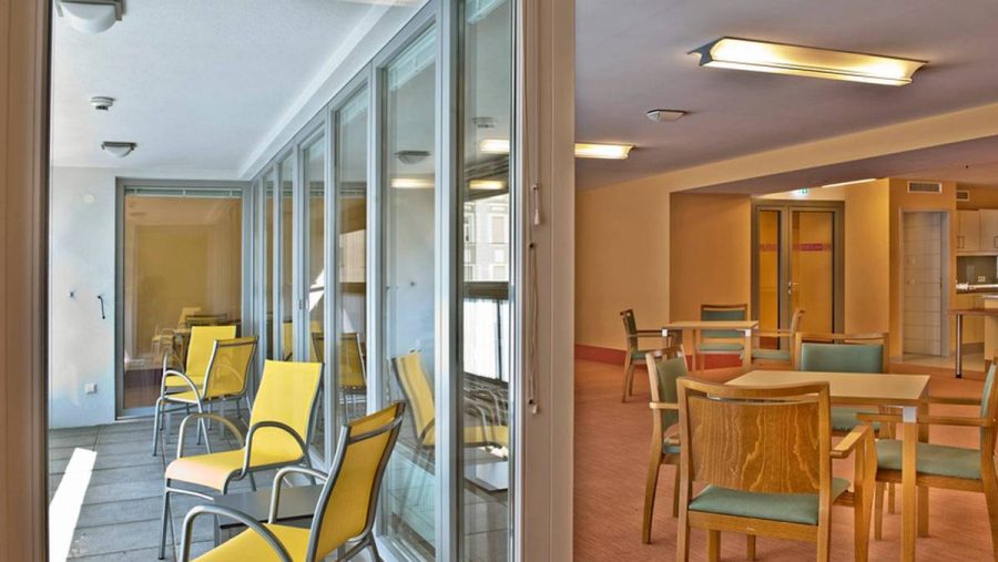 Helle Lounge mit gelben Stühlen und großen Fenstern in einer modernen Immobilie in Wien. Ideal zum Entspannen.