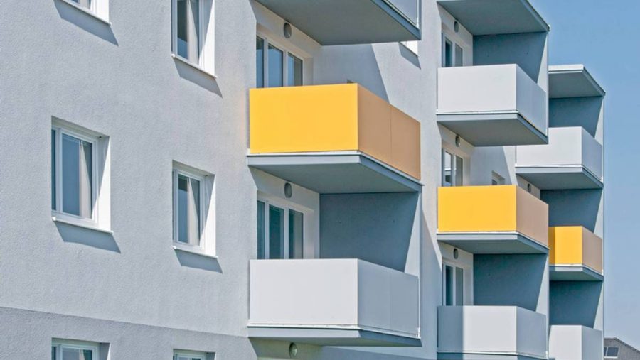 Moderne Wohnanlage mit gelben Balkonen, ideal für Wohnungskauf.