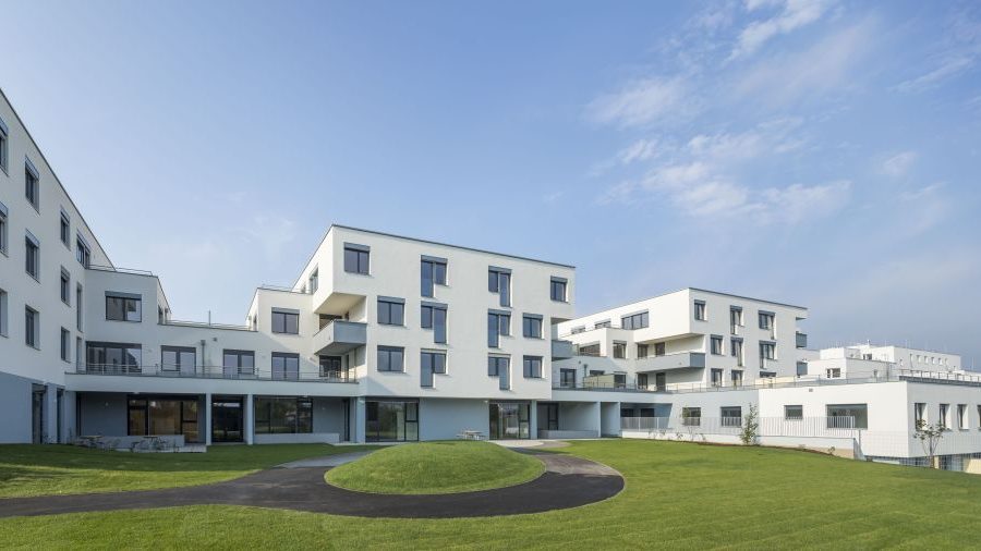 Moderne Wohnanlage mit grünem Rasen und klarem Himmel im Hintergrund.