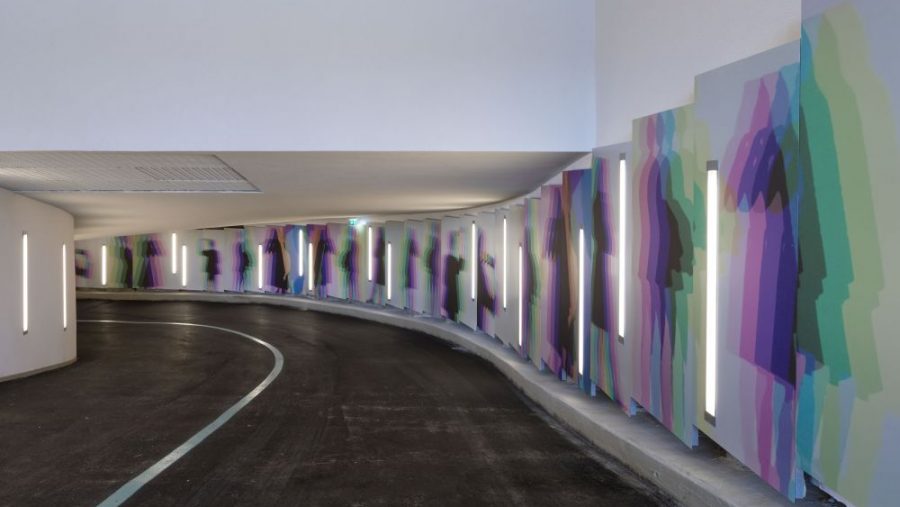 Kunstvolle Wandgestaltungen und Lichter in einer modernen Tiefgaragenausfahrt.