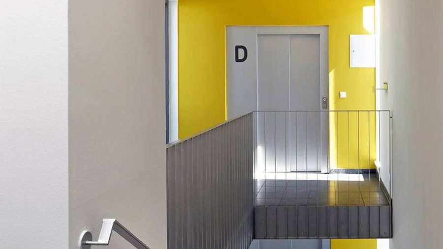 Moderner Eingangsbereich mit gelber Wand und Aufzug. Ideal für Immobilien in Wien.