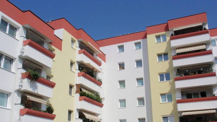 Mehrstöckiges Wohngebäude mit Balkonen in Wien bei klarem Himmel. Perfekt für Wohnungskauf.