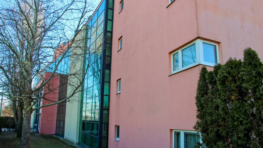 Moderne Immobilie mit großen Glasfenstern und pinker Fassade in ruhiger Lage in Wien. Ideal für Wohnungskäufer.