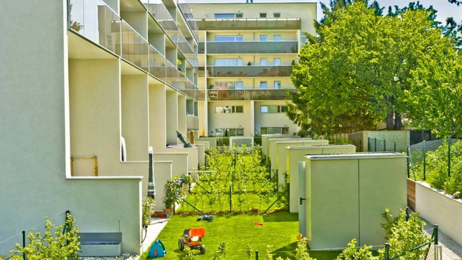 Moderne Wohnanlage mit grünen Gärten und Spielbereich für Kinder in Wien.