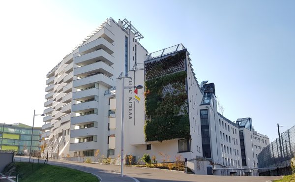 Moderne Wohngebäude mit vertikaler Begrünung unter klarem Himmel.