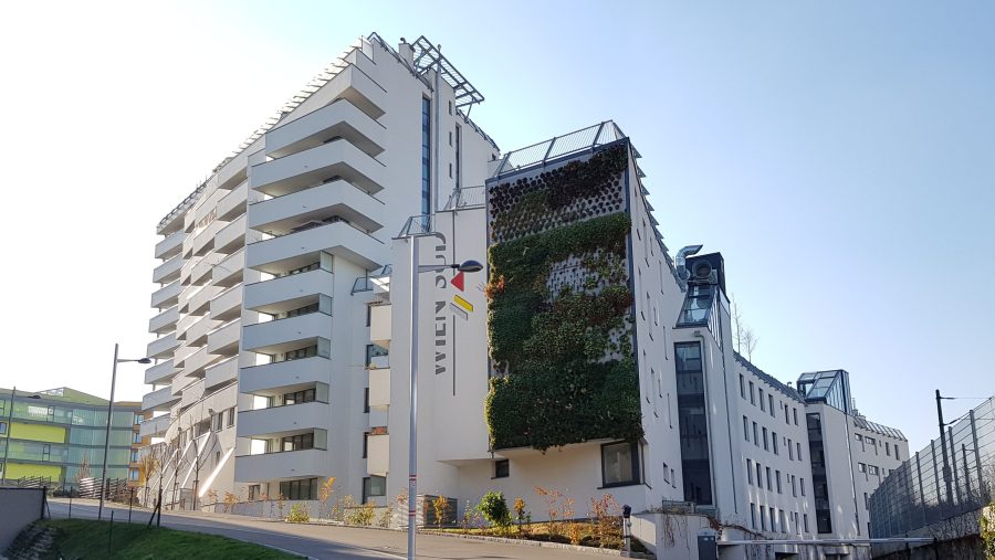 Moderne Wohngebäude mit vertikaler Begrünung unter klarem Himmel.