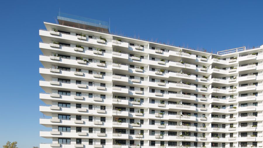 Moderne Wohnanlage mit Balkonen vor blauem Himmel.