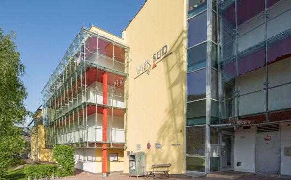 Moderne Gebäudefassade mit Glas und gelber Wand, bei Tageslicht fotografiert.