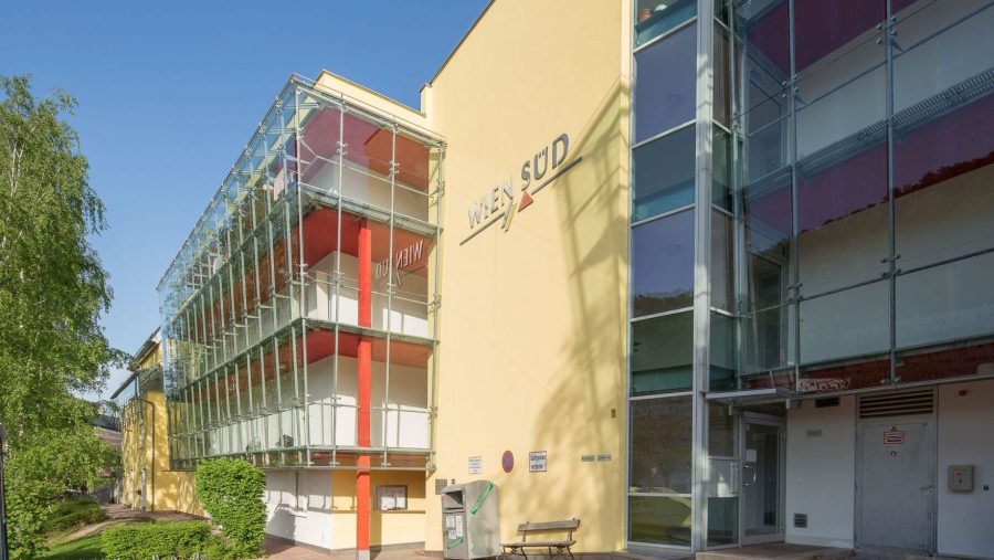 Moderne Gebäudefassade mit Glas und gelber Wand, bei Tageslicht fotografiert.