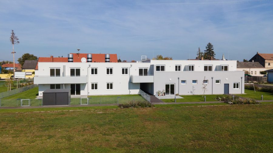 Modernes, zweistöckiges Gebäude in Wohngegend an einem sonnigen Tag mit grünem Rasen.