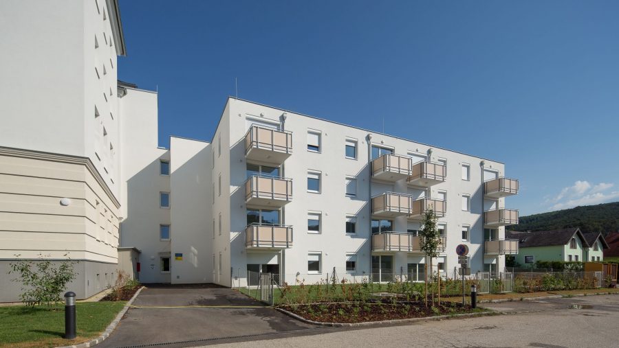 Moderne Wohnanlage mit Balkonen an einem sonnigen Tag, blaue Himmel im Hintergrund.