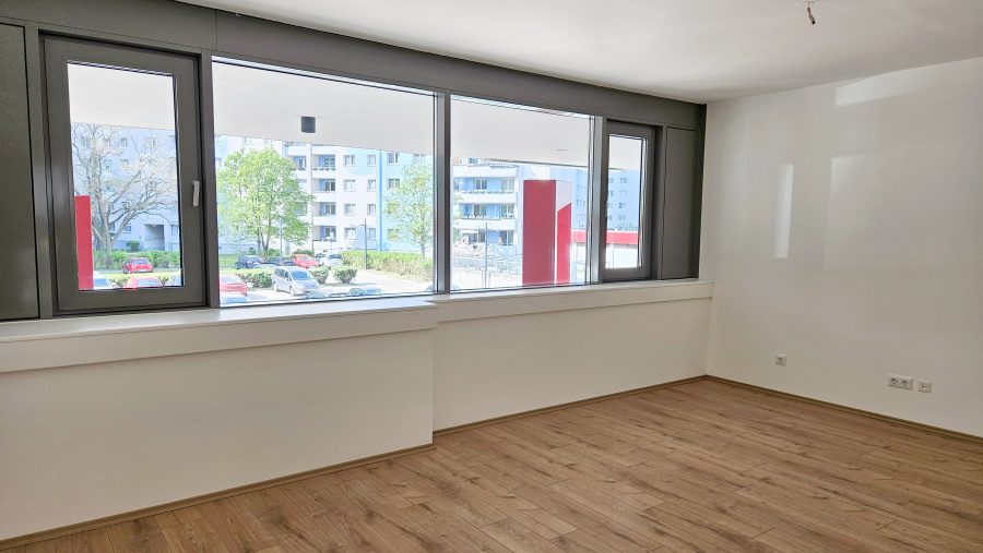Leerer Raum mit großen Fenstern, helles Licht und Holzboden. Ideal für Büro oder Wohnungseinrichtung.