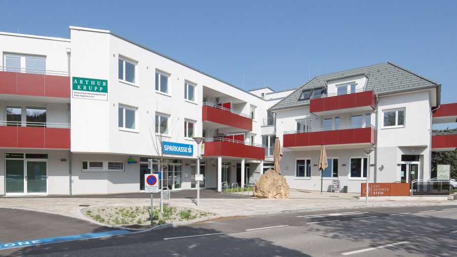 Moderne Gebäude mit Geschäftsschildern und Balkonen an einem sonnigen Tag.