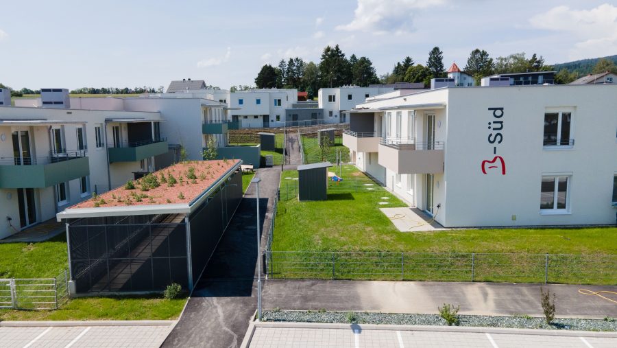 Moderne Wohnanlage mit begrüntem Dach, Balkonen und gepflegter Grünfläche bei sonnigem Wetter.