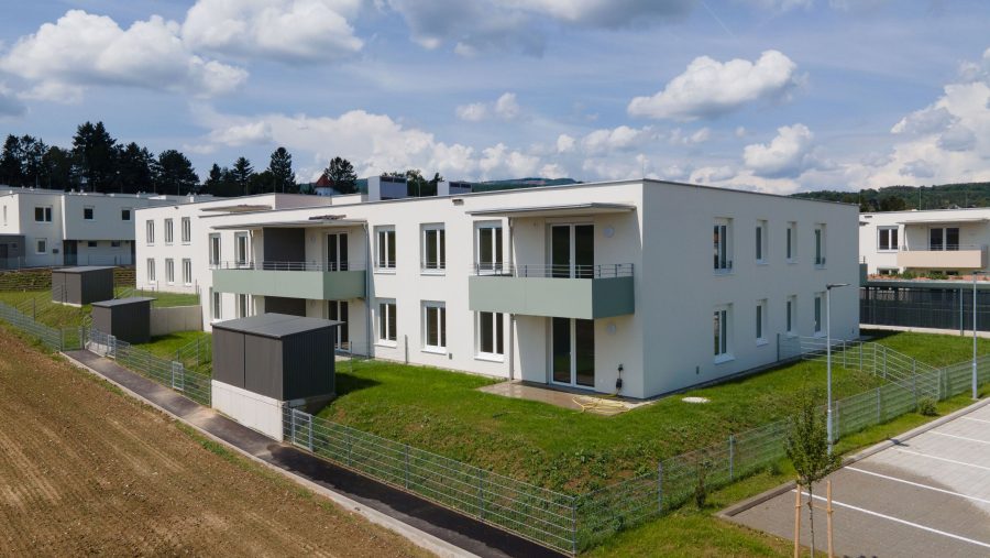 Moderne Wohngebäude mit Balkonen in einem Vorstadtgebiet unter blauem Himmel.