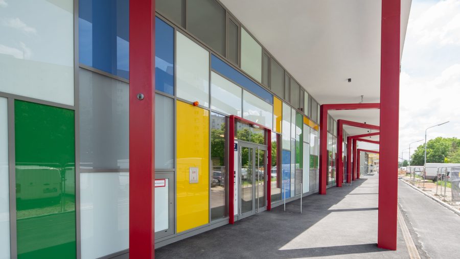 Moderne Architektur mit bunten Fassaden und roten Stützen unter blauem Himmel.