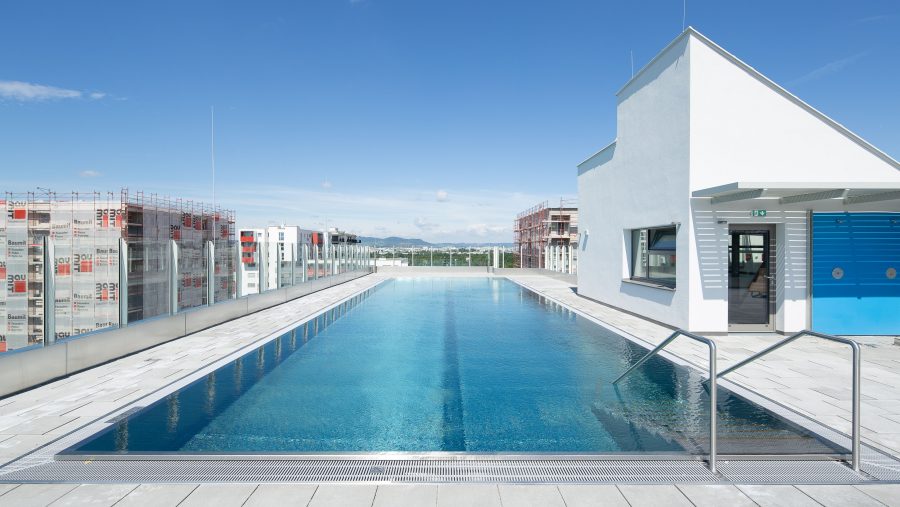 Dachterrassenpool mit blauen Himmel und modernen Gebäuden im Hintergrund.