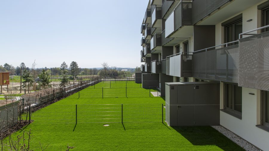 Moderne Wohnanlage mit Balkonen und gepflegtem Rasen an einem sonnigen Tag.