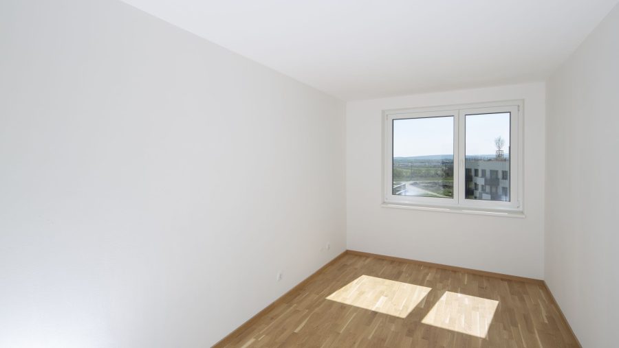 Leerraum mit Holzfußboden und Fenster mit Blick auf Landschaft.