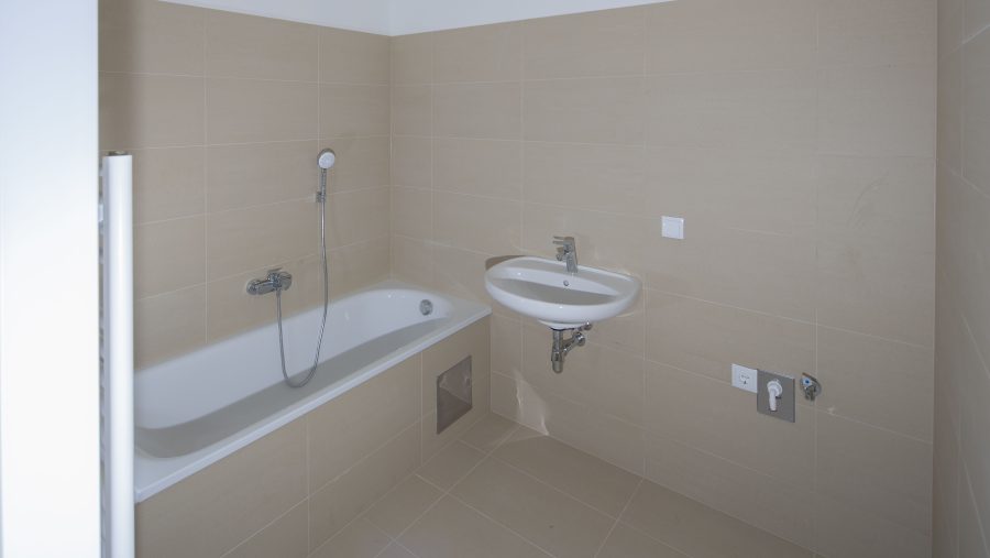Modernes Badezimmer mit Badewanne und Waschbecken, gefliest in Beige.