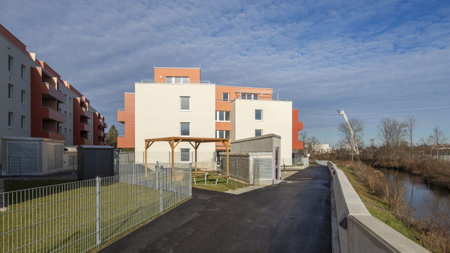 Moderne Wohngebäude bei sonnigem Wetter mit umliegendem Garten und Zugangspfad.