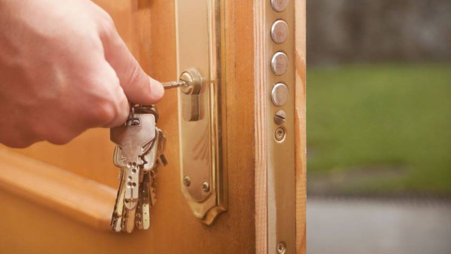 Hand dreht Schlüssel in Wohnungstür, symbolisiert Kauf der Immobilie.
