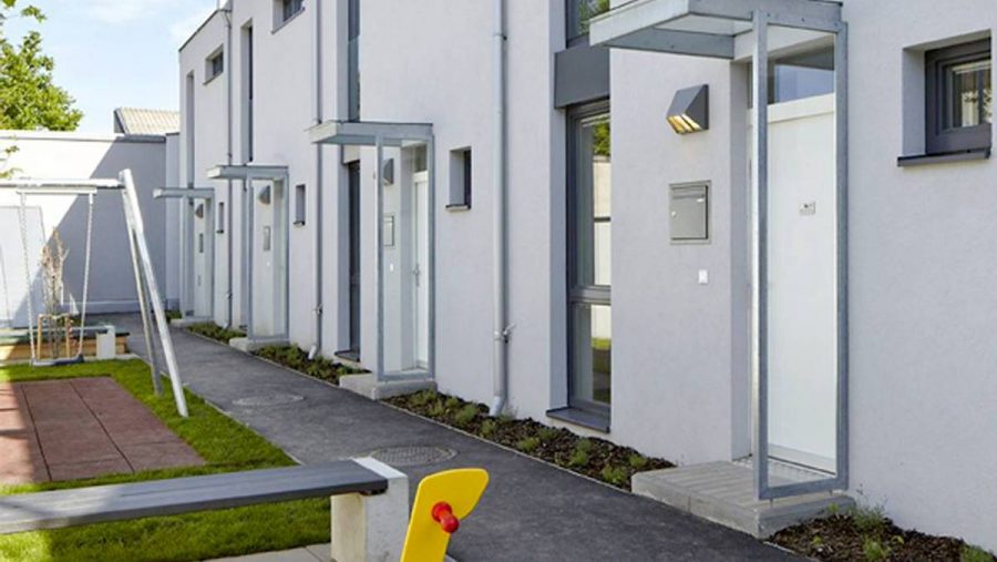 Moderne Wohnanlage mit Eingängen zu Wohnungen und Spielplatz für Kinder in der Nähe. Ideal für Familien in Wien.