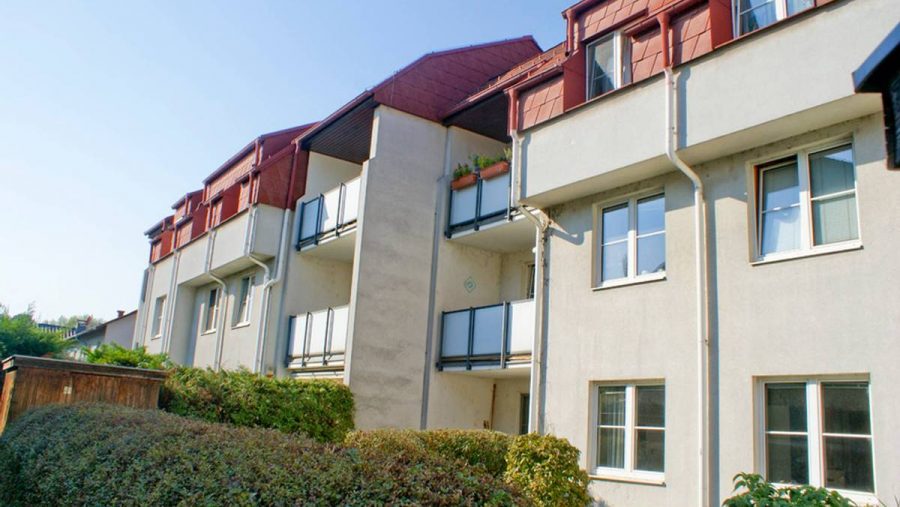 Mehrfamilienhaus mit Balkonen, gepflegte Grünanlage, moderne Architektur, ideal für Wohnung kaufen.