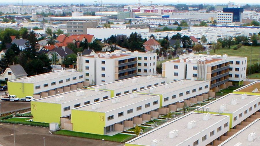 Moderne Wohnsiedlung mit mehreren mehrstöckigen Gebäuden und Häusern im urbanen Raum, umgeben von Grünflächen.