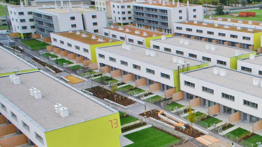 Wohnsiedlung mit modernen Gebäuden und grünen Dächern aus der Vogelperspektive.