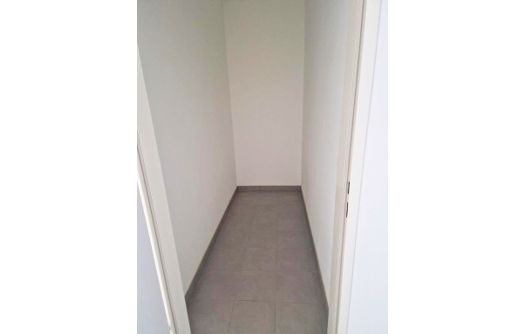 Schmaler, leerer Abstellraum mit weiß gestrichenen Wänden und grauem Bodenbelag.