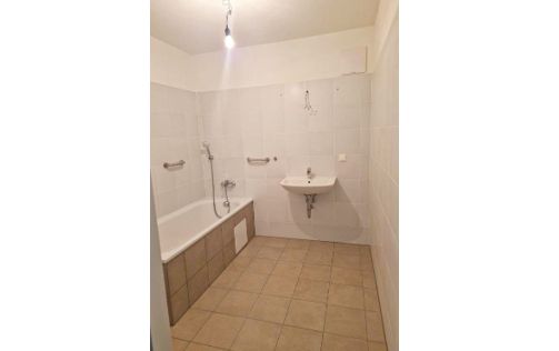 Helles Badezimmer mit Badewanne und Waschbecken in einer Immobilie in Wien.