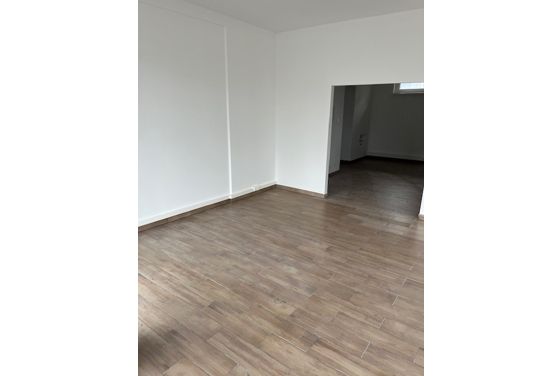 Leerer Raum mit weißen Wänden und Holzfußboden, potenzieller Wohnraum oder Bürofläche.