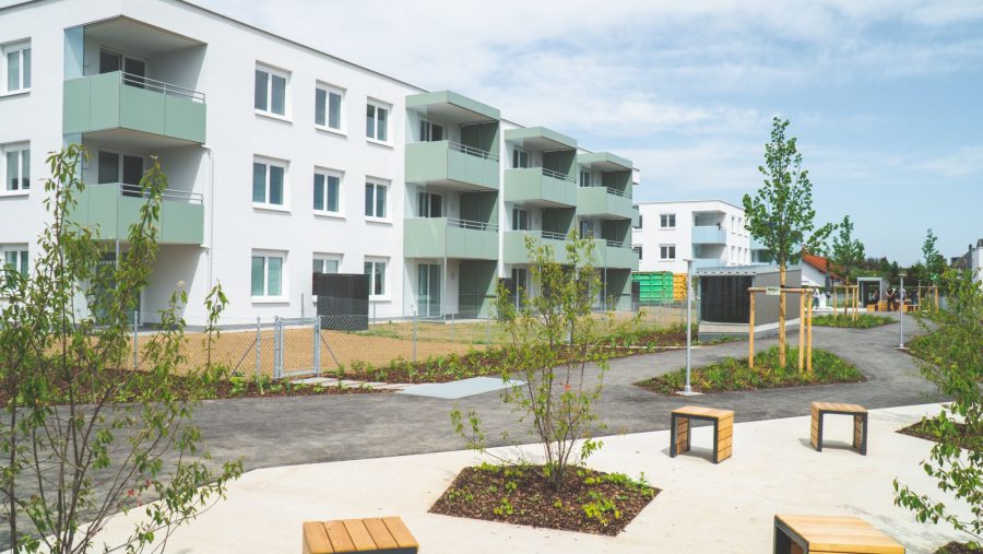 Moderne Wohnanlage mit Balkonen und gepflegtem Außenbereich bei klarem Himmel.