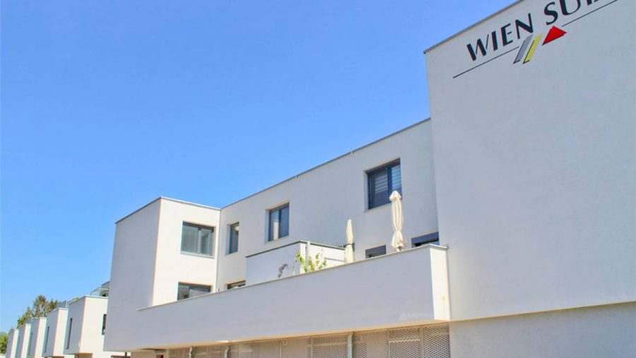 Moderne Wohngebäude mit klarer Architektur und blauem Himmel im Hintergrund.