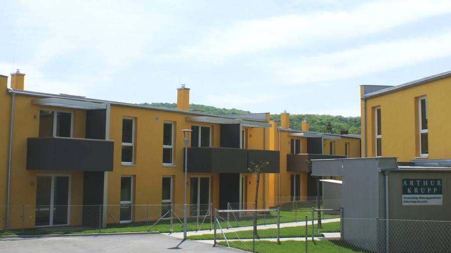 Moderne Wohnanlage in Wien mit gelben Fassaden und grüner Umgebung, ideal zum Wohnung kaufen.