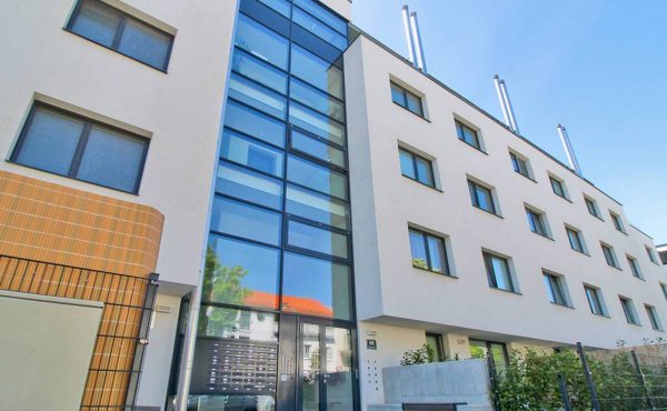 Moderne Fassade eines mehrstöckigen Bürogebäudes mit Glas- und Betonelementen bei sonnigem Himmel.