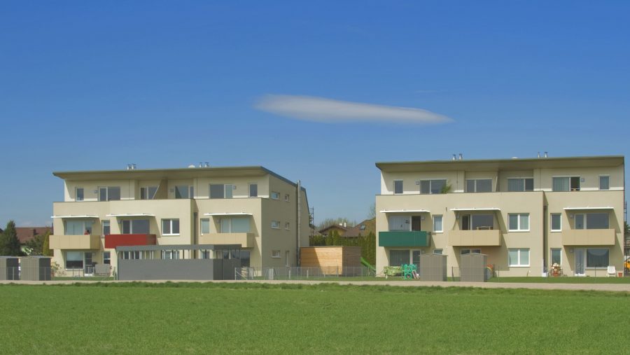 Moderne Neubauten mit Balkonen und grünem Rasen vor blauem Himmel, ideal für Wohnungssuchende in Wien.