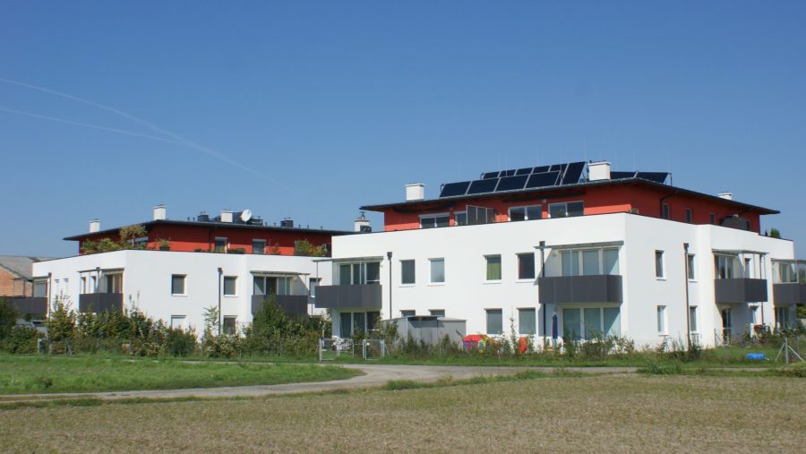 Moderne Wohngebäude mit Solarpanels auf dem Dach an einem sonnigen Tag.