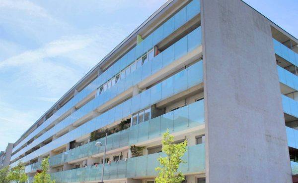 Moderne Wohngebäude mit Glasbalkonen bei klarem Himmel.