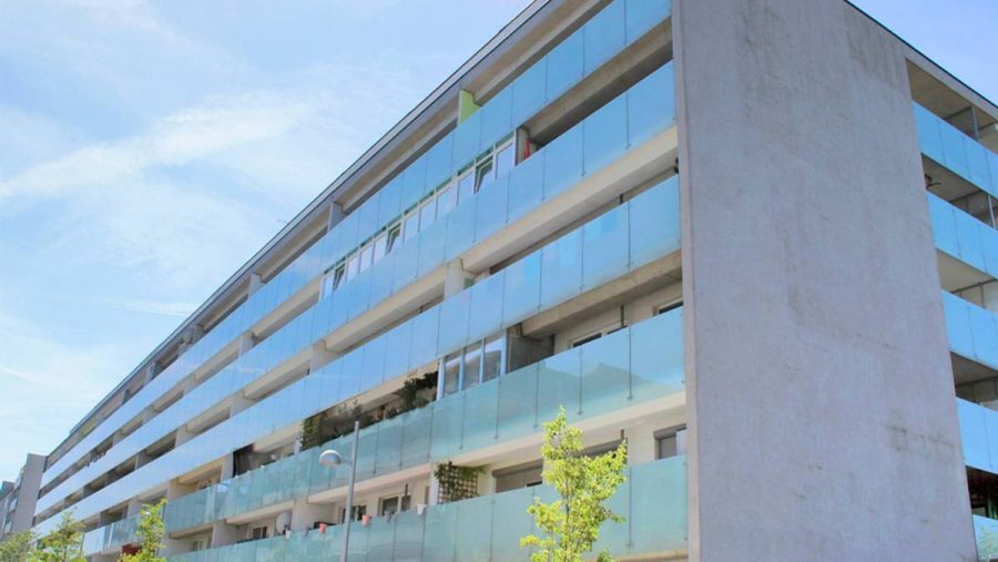 Moderne Wohngebäude mit Glasbalkonen bei klarem Himmel.
