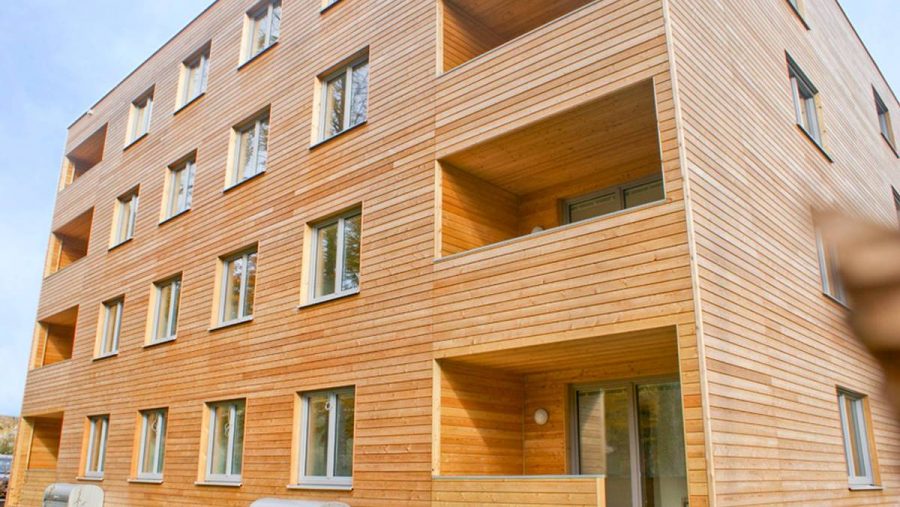 Mehrstöckiges Gebäude mit Holzfassade und mehreren Fenstern, moderner Bauweise.